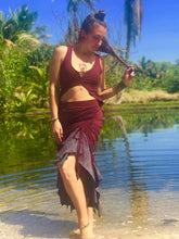Load image into Gallery viewer, A woman wears a soft cotton lycra two tone skirt that is red and grey with mandala print. The skirt is adjustable in length with cinch options on 4 sides. She is standing in front of palm trees on a beach in Hawaii.
